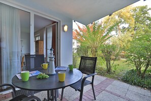 Un patio con una mesa redonda, sillas y un pequeño faro decorativo.