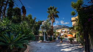 A courtyard with palm trees, a fountain, and a pool area. - Villa Amalia Resort (Cava de' Tirreni)
