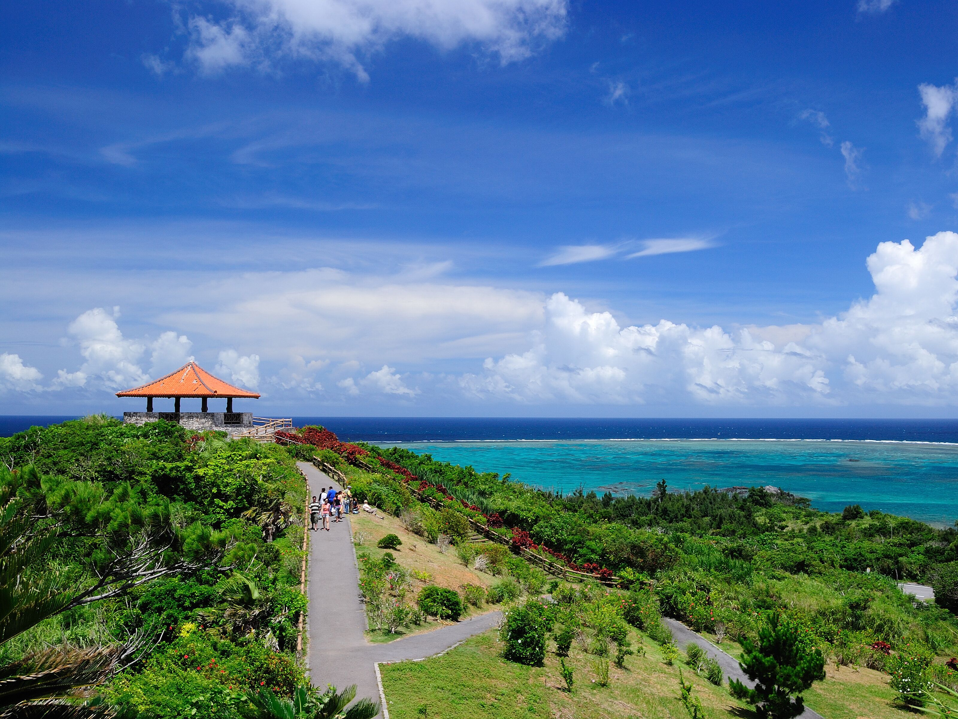 A gazebo with a tiled roof overlooking a coastal area with a clear sky and turquoise sea.