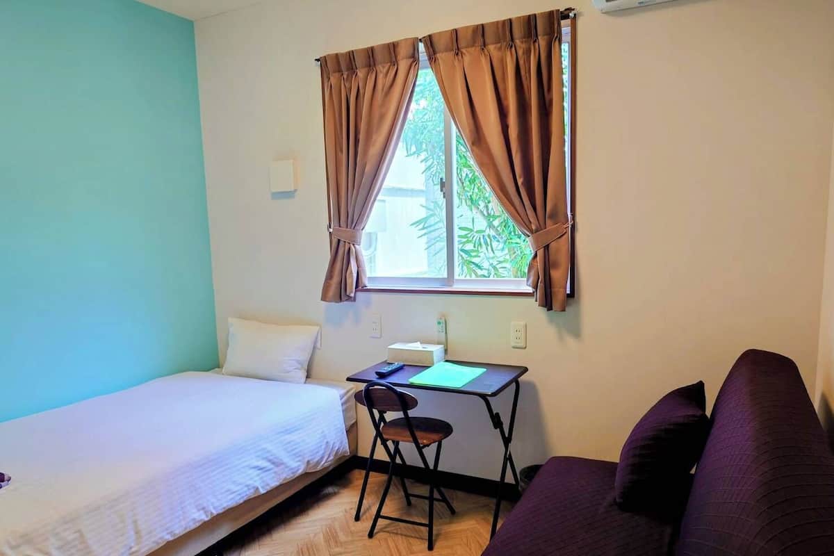 A small room with a bed, a desk with a chair, and a couch.