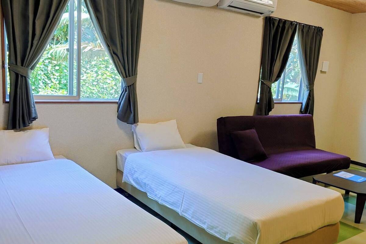 A hotel room with two beds, a sofa, and a small table.