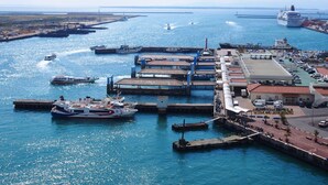 A marina with boats docked, a large ship, and a pier extending into the water.