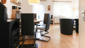 Un soggiorno moderno con camino, un'area pranzo con tavolo e sedie, e un'ampia finestra con tende.