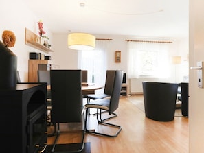 Uma sala de estar moderna com lareira, um espaço de jantar com mesa e cadeiras, e uma janela grande com cortinas.