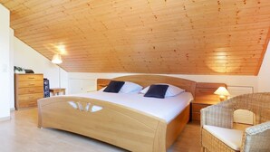 Una camera da letto con soffitto in legno, un letto, un comodino, una sedia e un armadio.