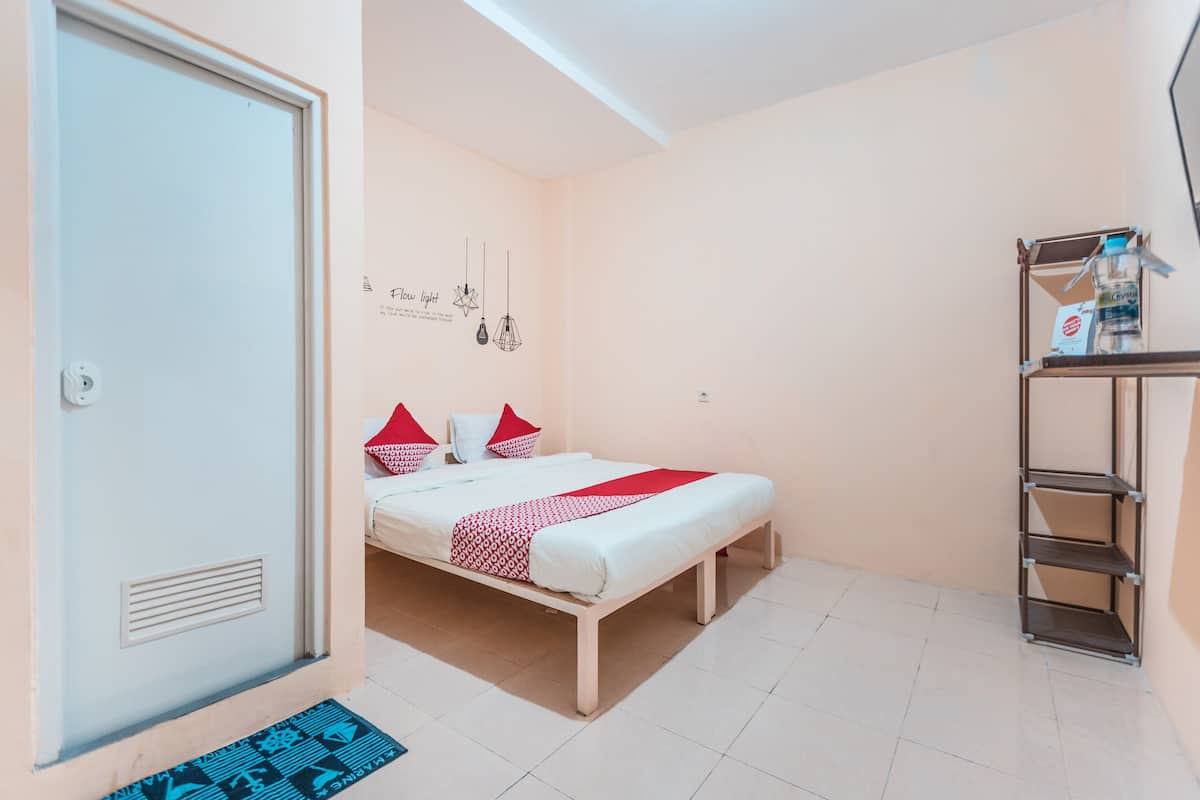 A bedroom with a bed, pillows, a shelf, and a door.