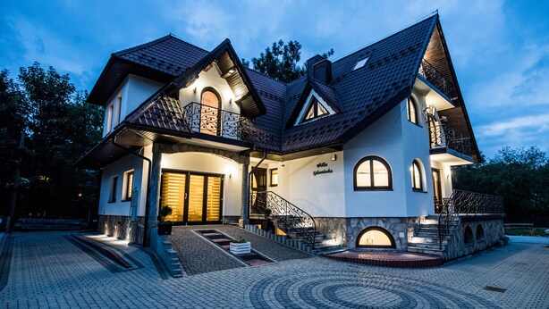 A large, two-story house with a stone facade, multiple windows, and a well-lit entrance. - Willa Galantowka (Zakopane)