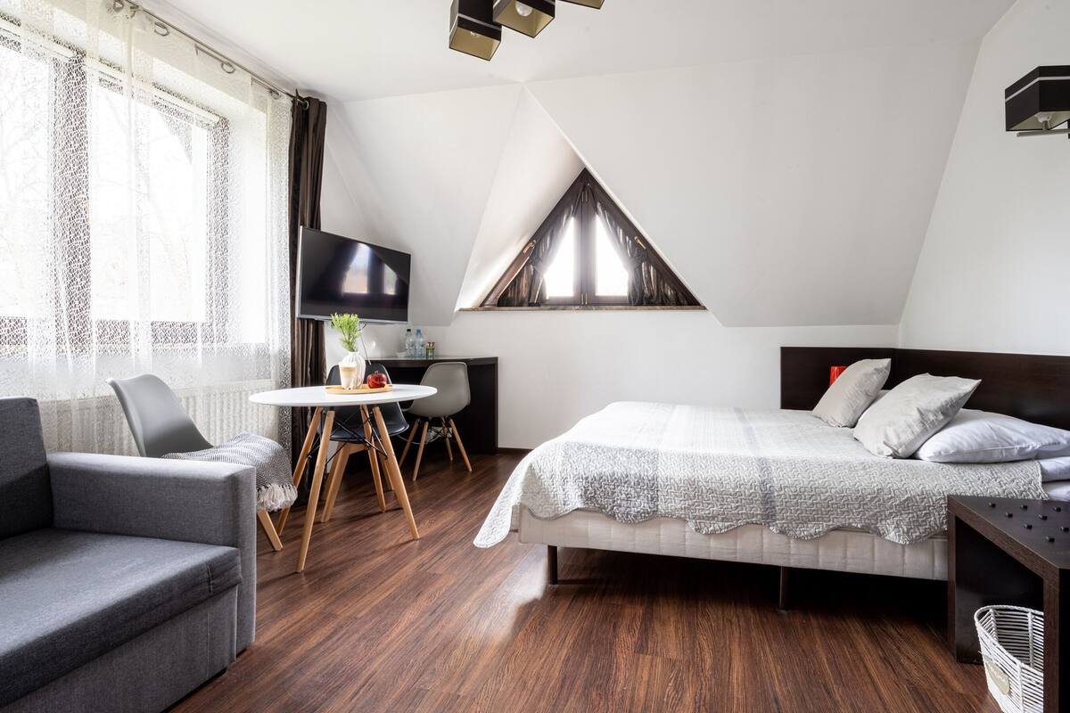 A modern bedroom with a bed, a desk, and a TV.