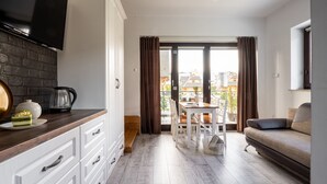 A modern kitchen with white cabinetry, a wooden countertop, and a flat-screen TV mounted above it. - Willa Galantowka (Zakopane)