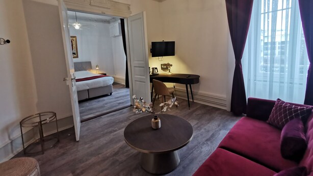 A modern hotel room with a bed, a desk with a computer, a round coffee table, and a sofa. - Colmar Suites (Colmar)