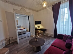 Ein modernes Hotelzimmer mit einem Bett, einem Schreibtisch mit Computer, einem runden Couchtisch und einer Couch.