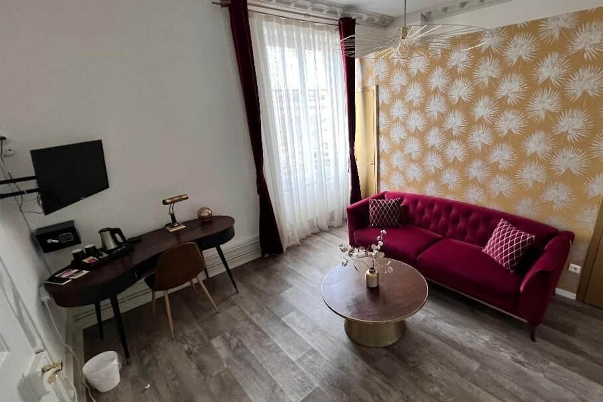 A living room with a red sofa, a coffee table, a TV, and a desk with a chair.