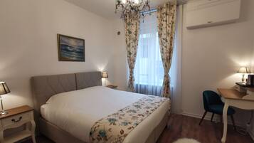 Une chambre à coucher avec un lit, un bureau, une chaise, un lustre et un tableau au mur.