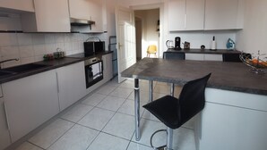 A modern kitchen with white cabinets, a black countertop, a stainless steel sink, a microwave, and a coffee maker. - Colmar Suites (Colmar)