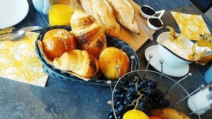 A breakfast table with croissants, bread, fruit, and juice. - Colmar Suites (Colmar)