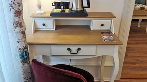 A wooden desk with a lamp, a coffee maker, and a magazine. There is a red chair in front of the desk. - Colmar Suites (Colmar)