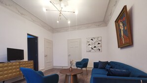 A modern living room with a blue sofa, a coffee table, and a TV on a wooden cabinet. - Colmar Suites (Colmar)