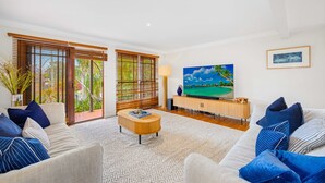 Sala de estar com sofá, mesa de centro, televisão e obras de arte.