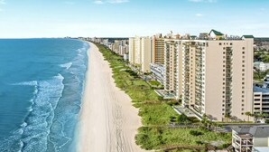 A coastal residential area with high-rise buildings, a sandy beach, and a clear blue sky.