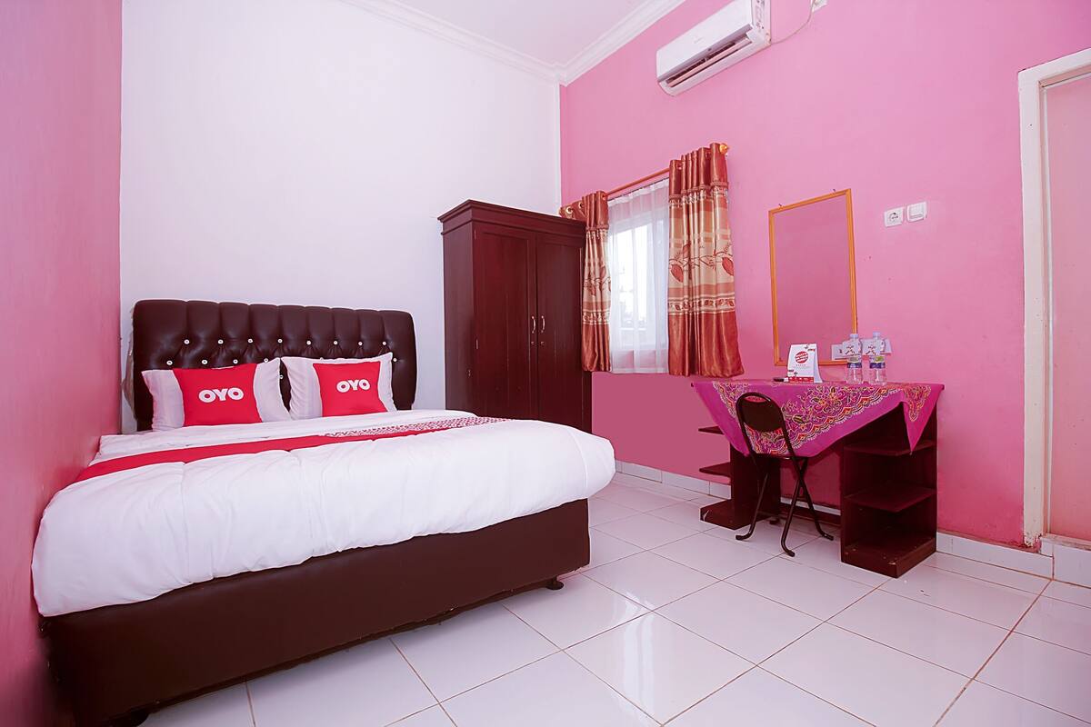 A bedroom with a bed, a desk, a chair, a wardrobe, and a mirror.