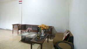 A room with a wooden bench, a glass-top table with a vase of flowers, and a brown sofa.