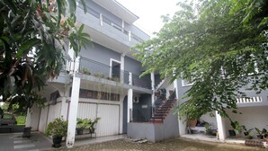 A multi-story building with a staircase leading to the upper floor. There are potted plants and a bench in the courtyard.