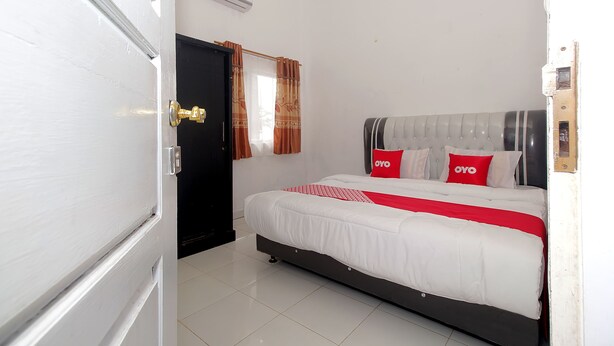 A bedroom with a bed, a black door, and a window with curtains.