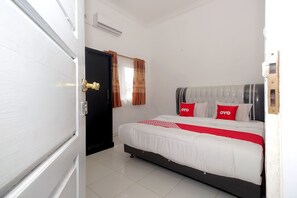 A bedroom with a bed, a black door, and a window with curtains.