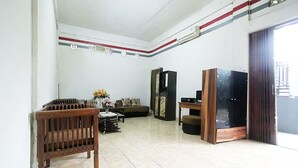 A living room with a sofa, wooden furniture, a TV, and a decorative vase.