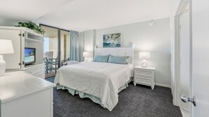 Un dormitorio con cama, mesitas de noche, televisión y vistas al exterior.