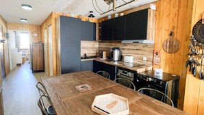Una cucina moderna con mobili in legno, un tavolo da pranzo in legno e una macchina per il caffè.