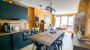 Una cucina compatta con mobili in legno, un tavolo da pranzo e una lampada a sospensione.