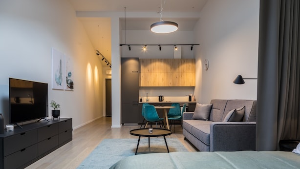 Une chambre d’hôtel moderne équipée d’un lit, d’une télévision, d’un bureau et d’une kitchenette.