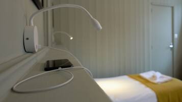 Une chambre d’hôtel avec un lit, une table de chevet avec une lampe et une prise de courant fixée au mur.