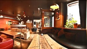 Un restaurante acogedor con mesas de madera, asientos de cuero, una zona de bar y un amplio ventanal con plantas.