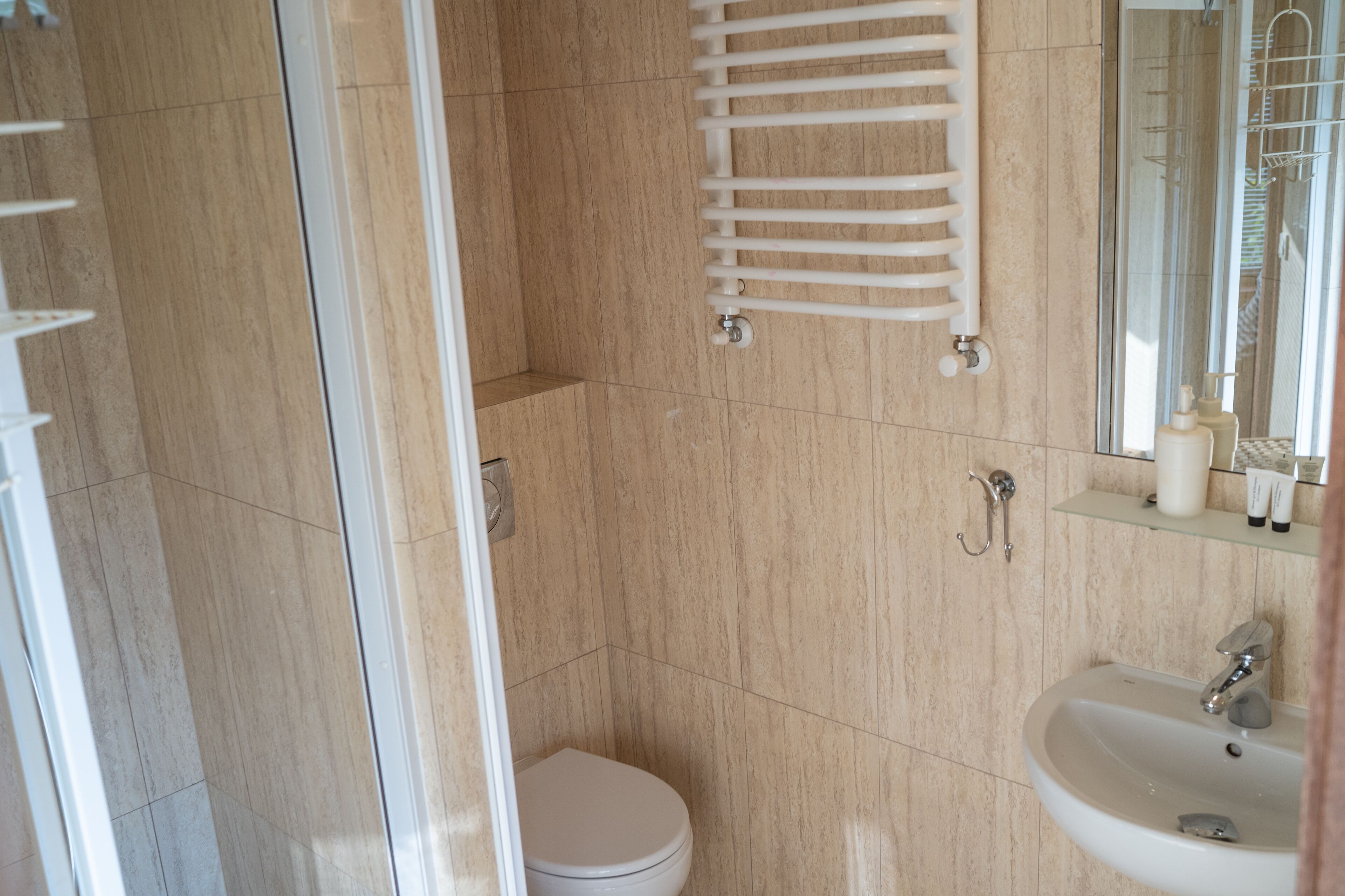 A modern bathroom with a toilet, a sink, a glass shower enclosure, and a towel rack.