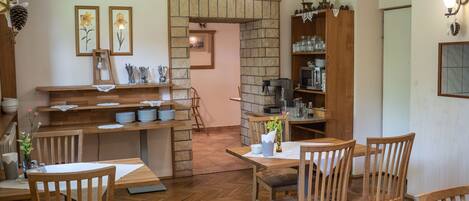 A cozy dining area with wooden furniture, a stone fireplace, and a coffee station.