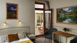 A hotel room with a bed, a desk, a chair, and a view of a mountain lake through a glass door. - Willa Iskra (Zakopane)