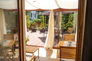 A patio area with wooden tables and chairs, potted plants, and a view of the surrounding garden. - Willa Iskra (Zakopane)