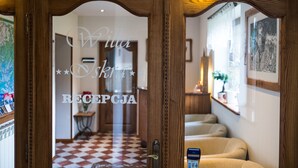 A reception area with a checkered floor, wooden reception desk, and a glass door with a nameplate. - Willa Iskra (Zakopane)