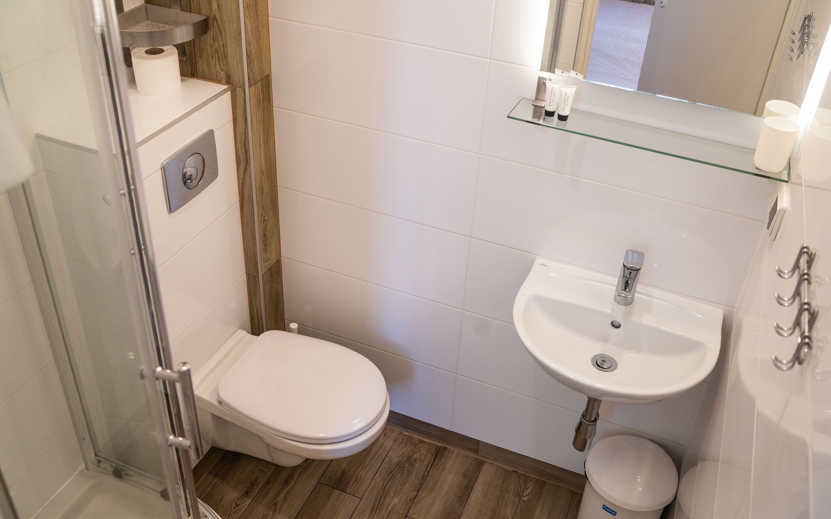 A small bathroom with a toilet, sink, and glass shelf.