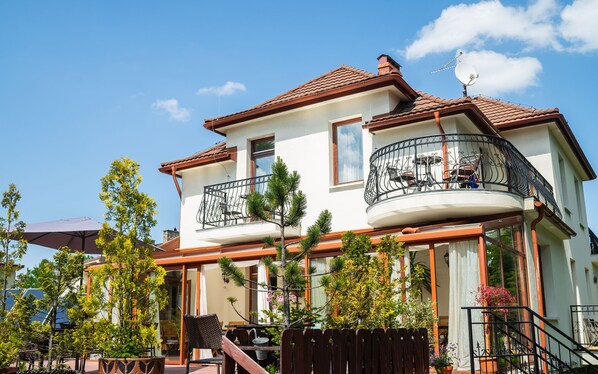 A two-story house with a balcony, a satellite dish, and a wooden fence. - Willa Iskra (Zakopane)