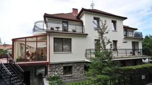 A two-story house with a balcony, a glass enclosure, and a stone facade. - Willa Iskra (Zakopane)