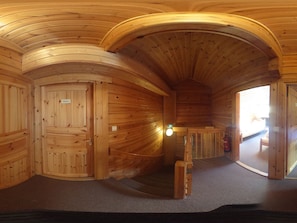 Een houten interieur met een gebogen plafond, een trap en een deur met een bordje.