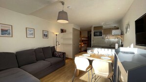 Ein kompakter Wohnbereich mit Sofa, Esstisch und Küchenzeile.