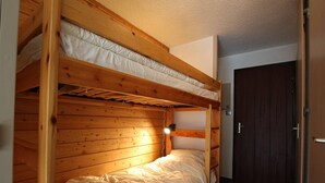 Ein Stockbett mit Holzbettgestell und weißer Bettwäsche.