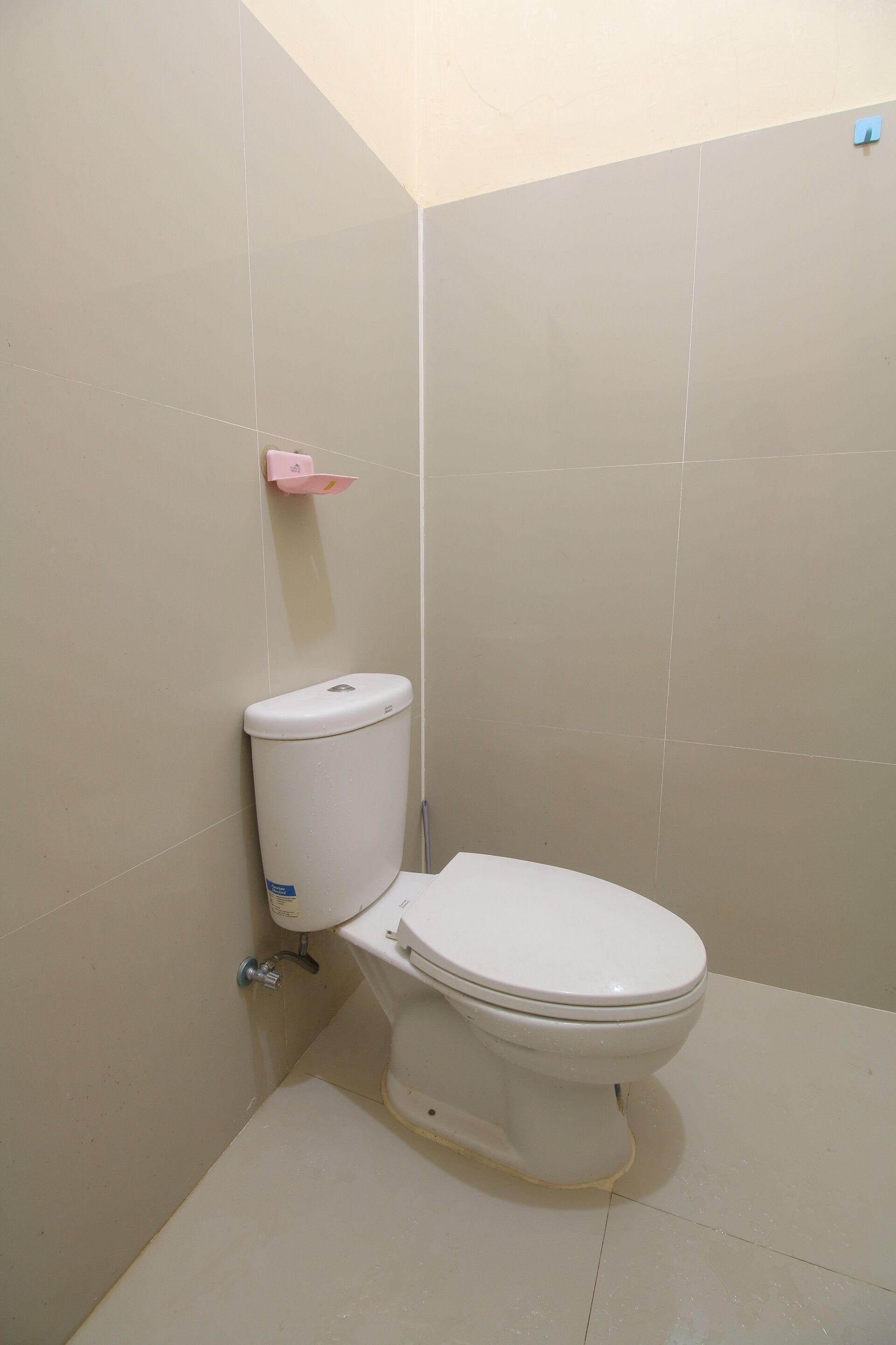 A bathroom with a toilet, a sink, and a wall-mounted soap dispenser.