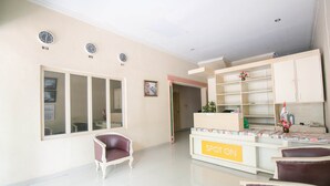 A reception area with a reception desk, a waiting area with chairs, and a wall with clocks. - Hotel O Grand Azizah (Makassar)