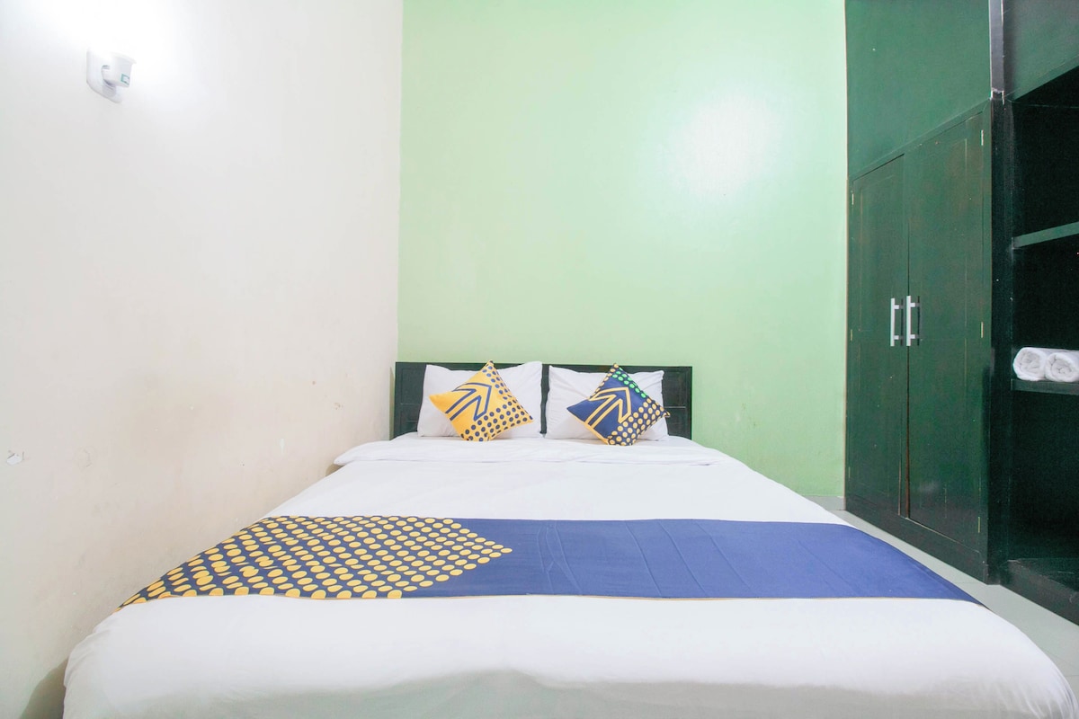 A bed with a blue and yellow patterned bedspread, two pillows with geometric designs, and a green wall.