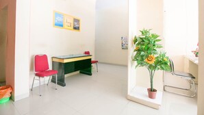 A room with a desk, two red chairs, a potted plant, and a bulletin board. - Hotel O Grand Azizah (Makassar)